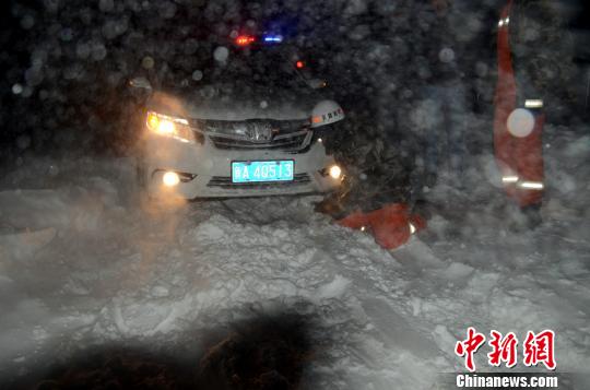 圖為消防人員跪在雪地里用鐵鍬鏟雪救援被困車輛?！±罱z